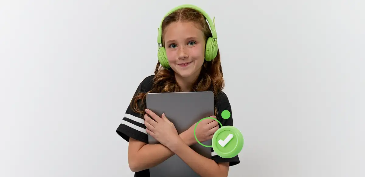 Elementary student wearing a green pair of headphones while holding her tablet